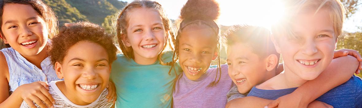 Helping Students Improve Their Social-Emotional Development and Function -Diverse group of children playing together in nature.