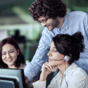 3 people grouped in front of a computer screen in an office environment while one of them points something out in the screen